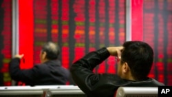 FILE - In this Oct. 31, 2018, photo, Chinese investors monitor stock prices at a brokerage house in Beijing. 