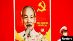 A Vietnamese soldier, wearing a protective mask, stands guard near an image of communist leader Ho Chi Minh at the National Convention Center in Hanoi on January 28, 2021. (Khan/Reuters)