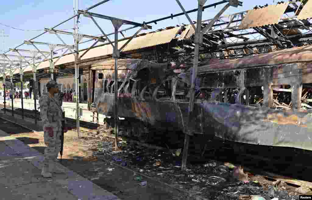 A paramilitary soldier stands near a damaged passenger carriage at the site of a bomb blast in the town of Sibi, Pakistan, April 8, 2014.