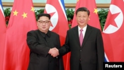 Pemimpin Korea Utara, Kim Jong-un (kiri) berjabat tangan dengan Presiden China XI JInping, di Dalian, China, 9 Mei 2018. (Foto: dok). 