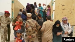 Iraqi soldiers help civilians, who fled from Falluja because of Islamic State violence, during a dust storm on the outskirts of Fallujah, Iraq, June 18, 2016