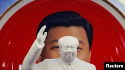 北京天安门附近一个纪念品商店里毛泽东的塑像摆在习近平纪念画盘的前面。（2018年3月1日）