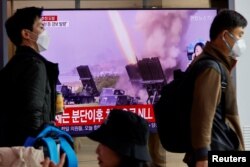 Men walk past a TV broadcasting a news report on North Korea firing a ballistic missile off its east coast, in Seoul, South Korea, Nov. 3, 2022.