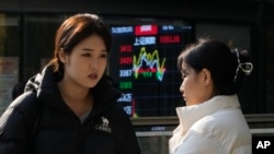 资料照：北京街头两名女子站在显示中国股市走势的展示板前。（2024年11月6日）