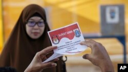 Seorang petugas pemungutan suara memeriksa surat suara saat putaran kedua pilgub Jakarta, 19 April 2017. (Foto: Associated Press)