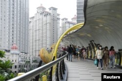 Orang-orang yang memakai masker pelindung berjalan di jembatan pusat perbelanjaan di Jakarta, 30 Oktober 2021. (Foto: REUTERS/Ajeng Dinar Ulfiana)