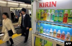 Para penumpang berjalan melewati mesin penjual otomatis Kirin yang menawarkan minuman dari raksasa minuman tersebut di peron kereta bawah tanah di Osaka. (Foto: AFP)