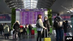 FILE - Travelers wait at the the departures board ahead of their flights at the Boryspil airport some 30 kilometers outside Kyiv on Feb. 13, 2022. 