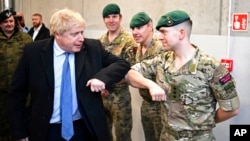 British Prime Minister Boris Johnson meets a member of the British Marines during a visit with his Polish counterpart, Mateusz Morawiecki, at the Warszawska Brygada Pancerna military base near Warsaw, Poland, Feb. 10, 2022.