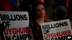 FILE - A protester holds a placard as she takes part in a demonstration against the holding of the 2022 Winter Olympic Games in China, at Piccadilly Circus in London, Feb. 3, 2022.
