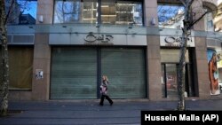 A woman passes a shuttered cosmetic shop on Hamra Street, Beirut, January 12, 2022. (Hussein Malla/AP)