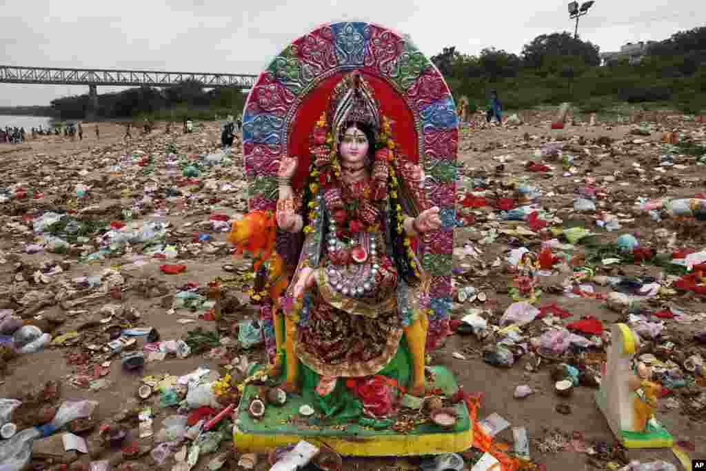 An idol of Hindu goddess Dashama stands among offerings and worship materials on the banks of the Sabarmati River after the end of the Dashama festival in Ahmadabad, India.