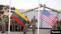 FILE - Soldiers hold Lithuanian and US flags during the opening ceremony of the US army camp Herkus in Pabrade, Lithuania, Aug. 30, 2021.