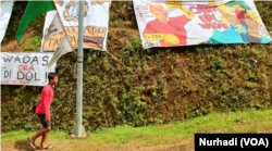 Seorang anak Wadas berjalan melewati spanduk yang menggambarkan Gubernur Jawa Tengah Ganjar Pranowo. (Foto: VOA/Nurhadi)