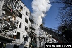 Petugas pemadam berusaha memadamkan api di sebuah gedung setelah pemboman di kota Chuguiv di Ukraina, 24 Februari 2022, saat Rusia mencoba menyerang Ukraina. (Foto: AFP/Aris Messinis)