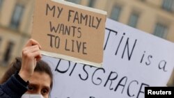 Demonstrators hold signs during an anti-war protest at Brandenburg Gate, after Russian President Vladimir Putin authorized a military operation in Ukraine, in Berlin, Feb. 24, 2022.