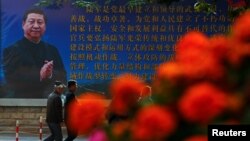 Những người đàn ông đi ngang qua một tấm áp phích của quân đội Giải phóng Nhân dân Trung Quốc (PLA) có hình một bức chân dung của Chủ tịch Tập Cận Bình. 