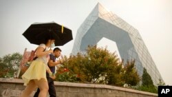 Seorang perempuan mengenakan masker di suatu hari yang penuh asap dan kabut di China