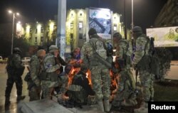 Para militan oposisi Suriah berkumpul di sekitar api unggun di Lapangan Saadallah al-Jabiri, setelah pemberontak mengklaim telah mencapai jantung Aleppo, Suriah, 30 November 2024. (Foto: Reuters)