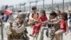 Seorang Marinir AS bermain dengan anak-anak yang menunggu untuk dievakuasi di Bandara Internasional Hamid Karzai di Kabul pada 20 Agustus 2021. (Foto: Korps Marinir AS via AFP)