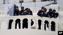 Policajci na položajima motre na demonstrante koji pokušavaju da se probiju kroz policijsku barijeru, 6. januara 2021, na Kapitol hilu, Vašington. (Foto: AP)