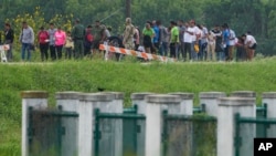 FILE - Migrants talk to officials along a road near the Rio Grande after crossing the Texas-Mexico border, May 11, 2023, in Brownsville, Texas. 