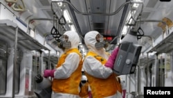 韩国工人为了防疫给首尔地铁车厢消毒。（2020年3月11日）