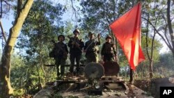 资料照片：缅甸民族民主同盟军成员在缴获的一辆缅甸陆军装甲车上举旗合影。（2023年10月28日）
