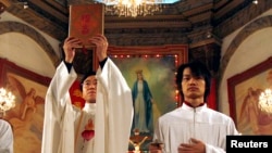 资料照： 北京天主教堂里的一名神职人员在做圣诞弥撒时高举中文版的圣经。（2007年12月24日）