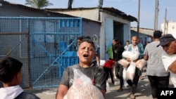 2023年10月28日,在代尔巴拉赫,巴勒斯坦人涌入联合国运营的一个援助供应中心,该中心向流离失所的家庭分发食品,此前以色列呼吁加沙北部100多万居民向南迁移,以确保安全.(法新社)