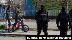 Montenegro, Podgorica, People pass behind a police checkpoint after the government tightened up measures for coronavirus 