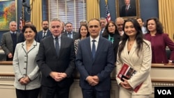 美国国会暨行政当局中国委员会主席克里斯·史密斯2024年12月5日在一场讨论中国共产党修改历史和磨灭少数族群文化的听证会后与维吾尔团体合影。(美国之音记者李逸华拍摄)