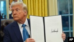 2025년 1월 31일 도널드 트럼프 미국 대통령이 워싱턴 D.C.의 백악관 집무실에서 행정명령에 서명 후 문서를 들어보이고 있다.