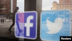 资料照：一家商店的橱窗上映照着推特和脸书的标识。