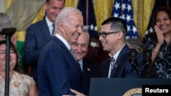 Javier Quiroz (kanan), migran yang memperoleh izin tinggal di AS melalui program DACA, memperkenalkan Presiden AS Joe Biden dalam sebuah acara di Gedung Putih, Washington, pada 18 Juni 2024. (Foto: Reuters/Anna Rose Layden)