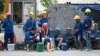 In this Monday Dec. 12, 2016 photo, Cambodian migrant construction workers wait for their transport home outside a building site in downtown Bangkok, Thailand.