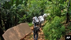 People carry ballot boxes to be distributed to polling stations ahead of the Feb. 14 election, in Kanekes village, Indonesia, Feb. 13, 2024.