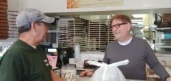 Primo Family Restaurant owner Jim Nicopoulos gives carryout food to a customer. (Deborah Block/VOA)