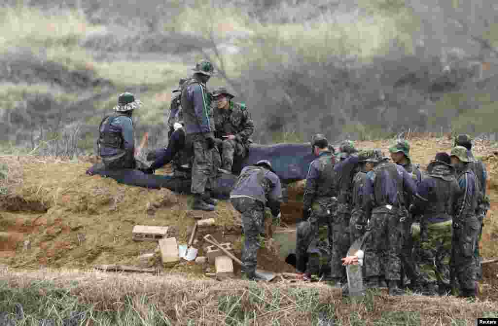 2013年4月15日,韩国士兵在分隔朝鲜半岛南北方的非军事区附近一边聊天一边修整战壕。