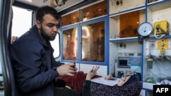 A young woman lies with papers and a phone inside an ambulance waiting at the Rafah border crossing in the southern Gaza Strip before receiving medical care in Egypt on Nov. 1, 2023.