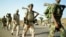 Eritrean soldiers march past displaced civilians as they redeploy near the town of Adi Quala on June 2.