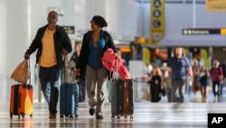 Sejumlah penumpang berjalan melalui area pemesanan tiket di Bandara Internasional Thurgood Marshall di Baltimore, pada 25 November 2024. (Foto: AP/Stephanie Scarbrough)
