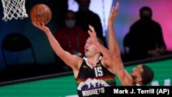 Nikola Jokić postiže poene pored Rudija Gobera, u drugom poluvremenu sedme utakmice prvog kola plej-ofa u Orlandu (Foto: AP/Mark J. Terrill)