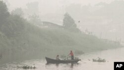 Seorang pria mendayung perahu di Sungai Siak, mementos asap tipis akibat kebakaran hutan di kota Pekanbaru, Riau province, Indonesia (5/10).