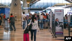 Seorang penumpang mengenakan masker, berjalan di Bandara Internasional Kuala Lumpur (KLIA), Sepang 29 November 2021, saat negara-negara di seluruh dunia menutup perbatasan dan memperbarui pembatasan perjalanan sebagai tanggapan atas penyebaran varian Omicron.