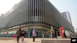 Residents walk past an Evergrande commercial complex with a shuttered Evergrande auto showroom in Beijing, Jan. 29, 2024. Chinese property developer China Evergrande Group was ordered to liquidate by a Hong Kong court, after the firm was unable to reach a restructuring deal. 