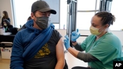 Brian Kennedy (kiri), seorang guru olahraga SD menerima vaksinasi COVID-19 di di Denver, Colorado (foto: dok). 