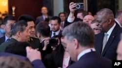 美国防长奥斯汀（右一）与中国防长李尚福（左一）在新加坡的香格里拉对话会议期间握手。（2023年6月2日）