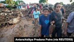 Seorang perempuan menangisi kerabatnya yang ditemukan tewas akibat banjir bandang yang dipicu hujan lebat di Flores Timur, Nusa Tenggara Timur, 6 April 2021. (Foto: Antara/Aditya Pradana Putra via REUTERS)