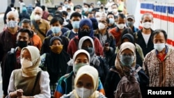 Orang-orang yang memakai masker berjalan di peron stasiun kereta api di tengah merebaknya varian Omicron COVID-19 di Jakarta, 3 Januari 2022. (REUTERS/Willy Kurniawan)